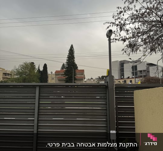 מצלמת אבטחה מותקנת על עמוד ליד גדר מתכת